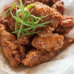Crispy Korean fried chicken coated in sweet chili sauce served with side dishes
