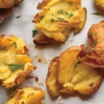 Crispy smashed potatoes topped with garlic and herbs, showcasing their golden exterior.