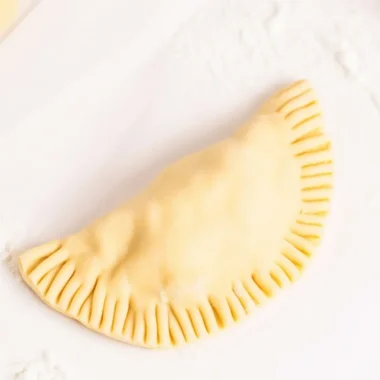 Homemade empanada dough ready for baking or frying, showcasing a flaky texture.