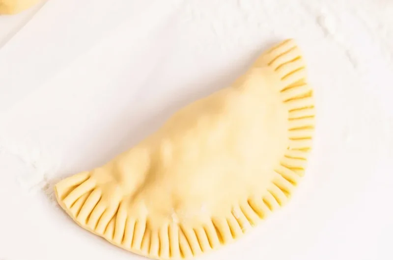 Homemade empanada dough ready for baking or frying, showcasing a flaky texture.