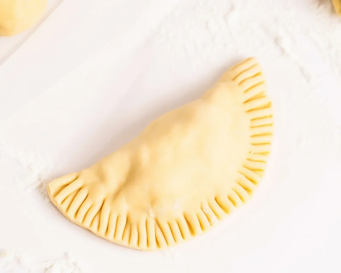 Homemade empanada dough ready for baking or frying, showcasing a flaky texture.