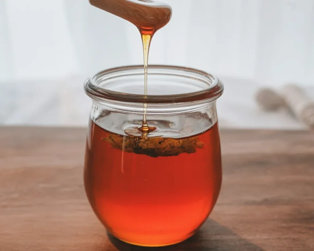 A jar of Hot Honey infused with chilies, perfect for drizzling on various dishes.