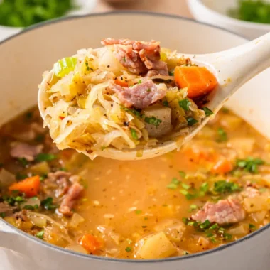 Bowl of German Sauerkraut Soup (Sauerkrautsuppe) garnished with herbs.