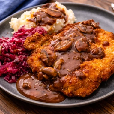 Authentic Jägerschnitzel with pork cutlets and creamy mushroom gravy served on a plate.